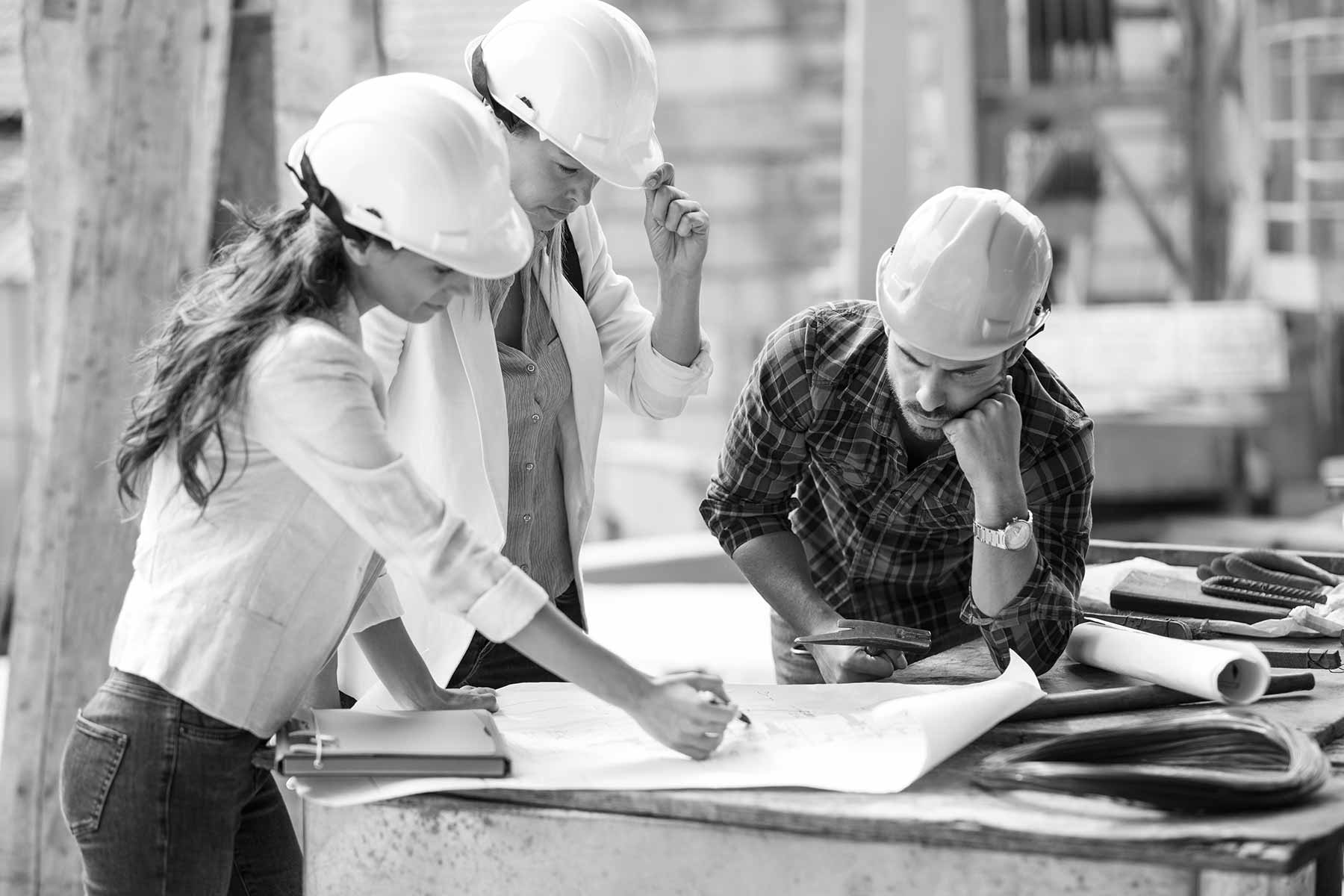 Männer und Frauen auf einer Baustelle, Plan lesend