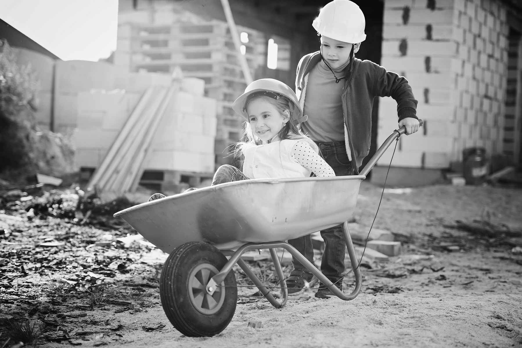 Zwei Kinder, die spielen und mit einer Schreibtruhe fahren